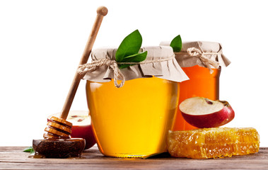 Glass cans full of honey, apples and honeycombs on wood. Clippin