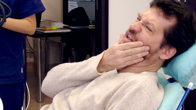 Man feeling strong teeth ache at dentist studio