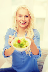 smiling young woman with green salad at home