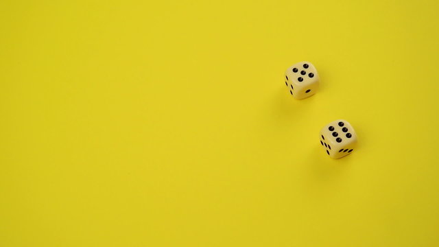 Rolling Dice on Yellow Background as Gambling Concept