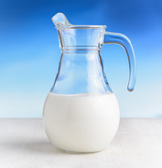 Jug of milk on sky background. Half full pitcher