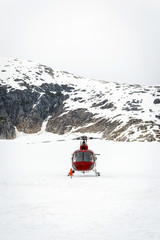 Helicopter landing on glacier in between snowy mountains