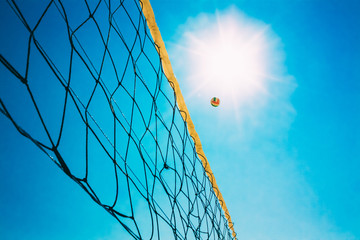 Volleyball Ball Over Net On Background Of Blue Summer Sunny Sky