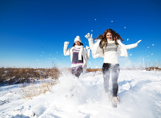 Two girlfriends have fun and enjoy fresh snow at beautiful winte