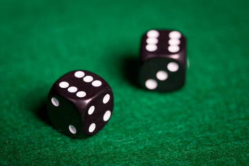 close up of black dice on green casino table