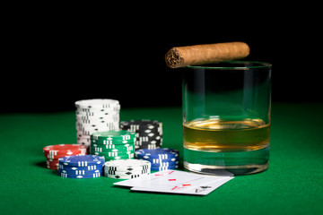 close up of chips, cards whisky and cigar on table