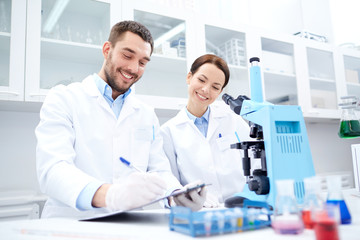 scientists with clipboard and microscope in lab