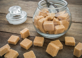Brown sugar cubes and jar on wooden table