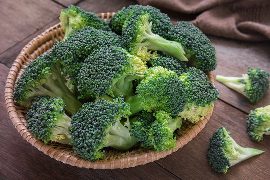 Fresh broccoli in basket on wooden table
