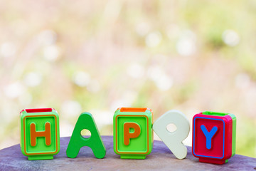 Colorful wooden and toy word happy on meadow background