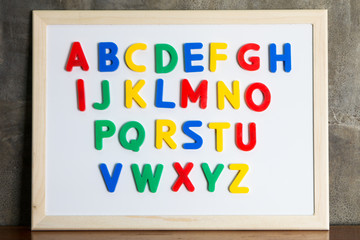 Magnet plastic alphabet on whiteboard on cement wall background