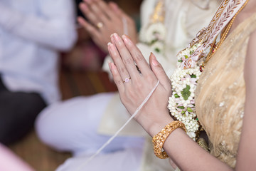 Thai groom wearing wedding ring for his bride