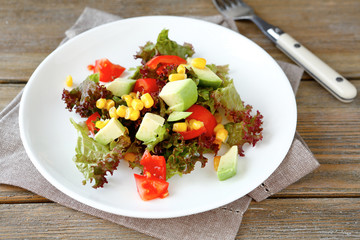 salad with avocado, tomatoes and corn on a white plate