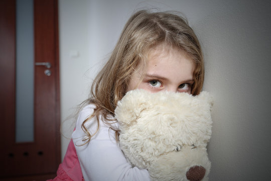 Young sad girl huging a teddy bear