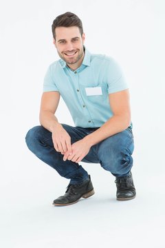 Handsome delivery man crouching on white background