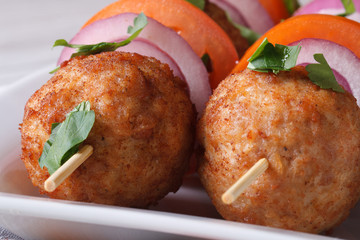 Fried meatballs on skewers with vegetables macro. Horizontal