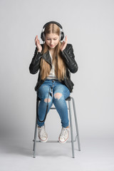 Girl in wired headphones is sitting and listening music