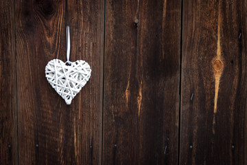 White wicker heart on wooden background