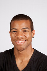 Black man in black shirt smiling at the camera