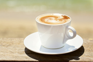 Cappuchino or latte coffe in a white cup with heart shaped foam