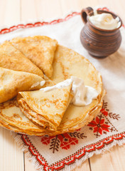Pancakes with a sour cream on wooden table