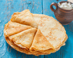 Pancakes with a sour cream on wooden table