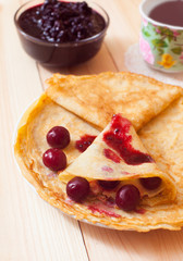 Stack of delicious pancakes with berries on plate on wooden back