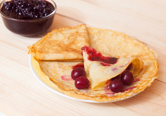 Stack of delicious pancakes with berries on plate on wooden back