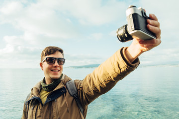 Obraz premium Happy man takes photographs self portrait on coastline