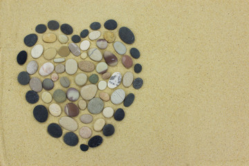 Pebble beach stone heart on golden sand