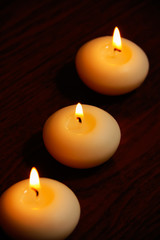 Fototapeta na wymiar Three candles on a dark wooden table.
