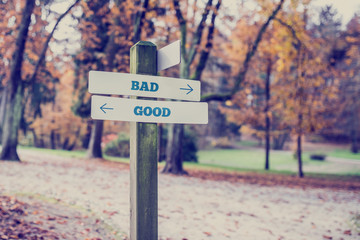 Rustic wooden sign in an autumn park with the words Bad - Good