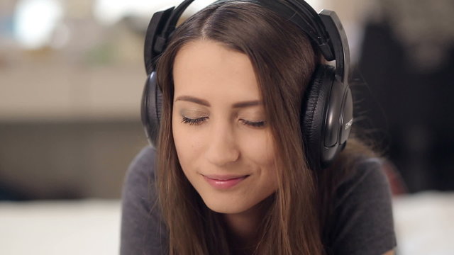 Girl Lying on the Bed, Enjoying Music in Headphones