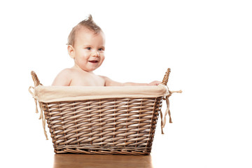 Happy little baby boy sitting in a wicker basket