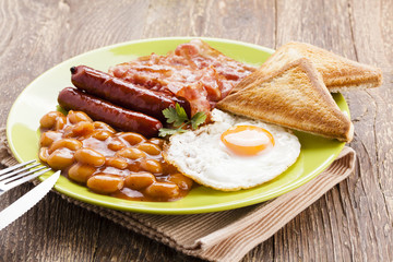Full english breakfast with bacon, sausage, fried egg, baked bea
