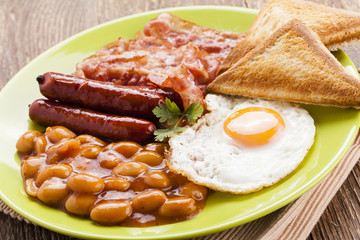 Full english breakfast with bacon, sausage, fried egg, baked bea