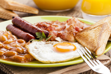 Full english breakfast with bacon, sausage, fried egg, baked bea