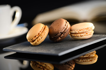three macaroon on a slate with espresso coffee on background