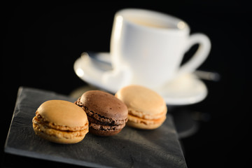 three macaroon on a slate with espresso coffee on background