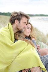 Couple sitting on sand - windy autumn day on the beach