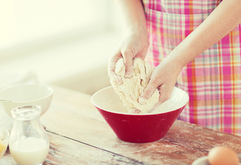 close up of female hands kneading dough at home