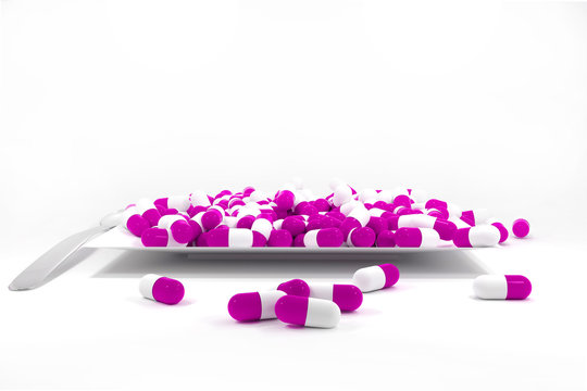large pile of purple colored pills on white plate
