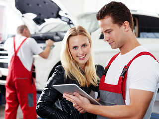 Customer and mechanic in a garage look at a quotation