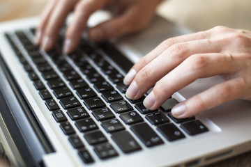 Women's fingers typing on laptop keyboard.