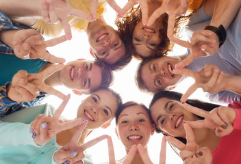 group of smiling teenagers showing victory sign