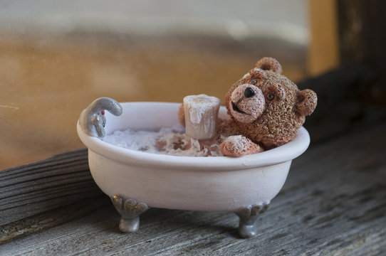 Teddy bear taking bath with a cup of beer