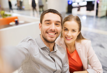 happy couple taking selfie in mall or office