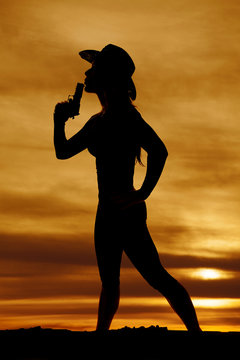 silhouette of woman cowboy hat with gun blow