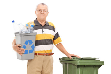 Senior holding recycle bin and standing by trash can