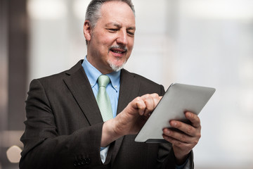 Smiling man using his tablet computer